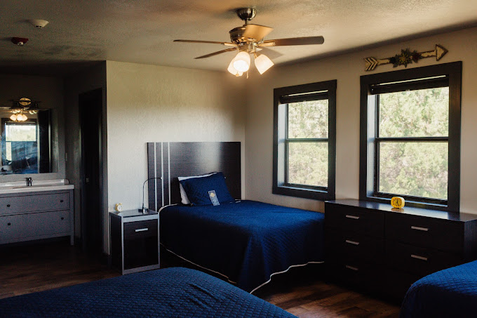 Room with twin beds, dressers, and large windows