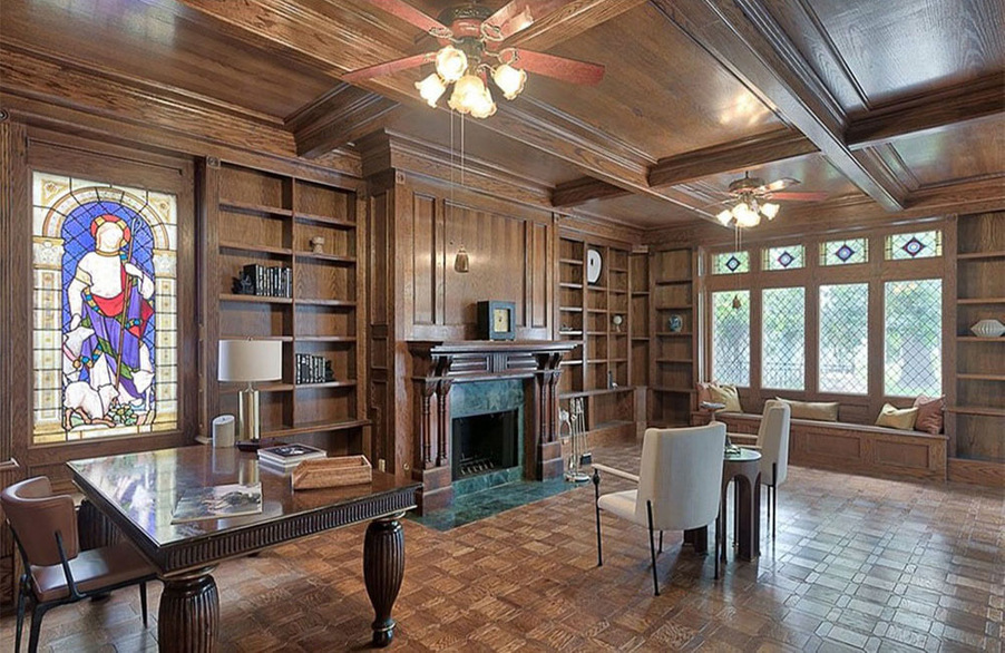 Study with chairs, a fireplace, and bookshelves.