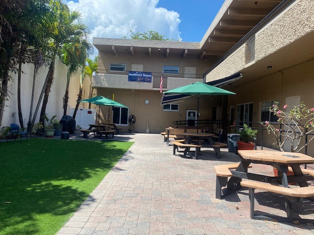 Outdoor courtyard with picnic tables, umbrellas, and greenery.