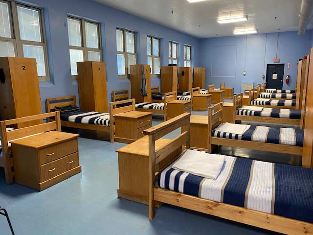 Shared dorm room with wooden beds and lockers