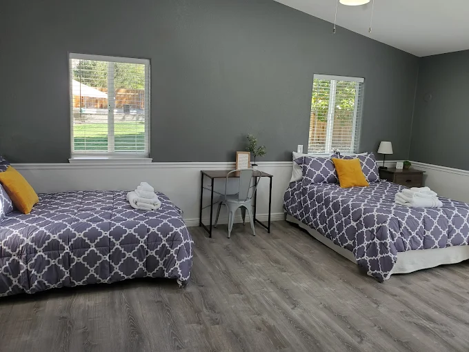 Shared bedroom with two beds, gray bedding, and bright windows