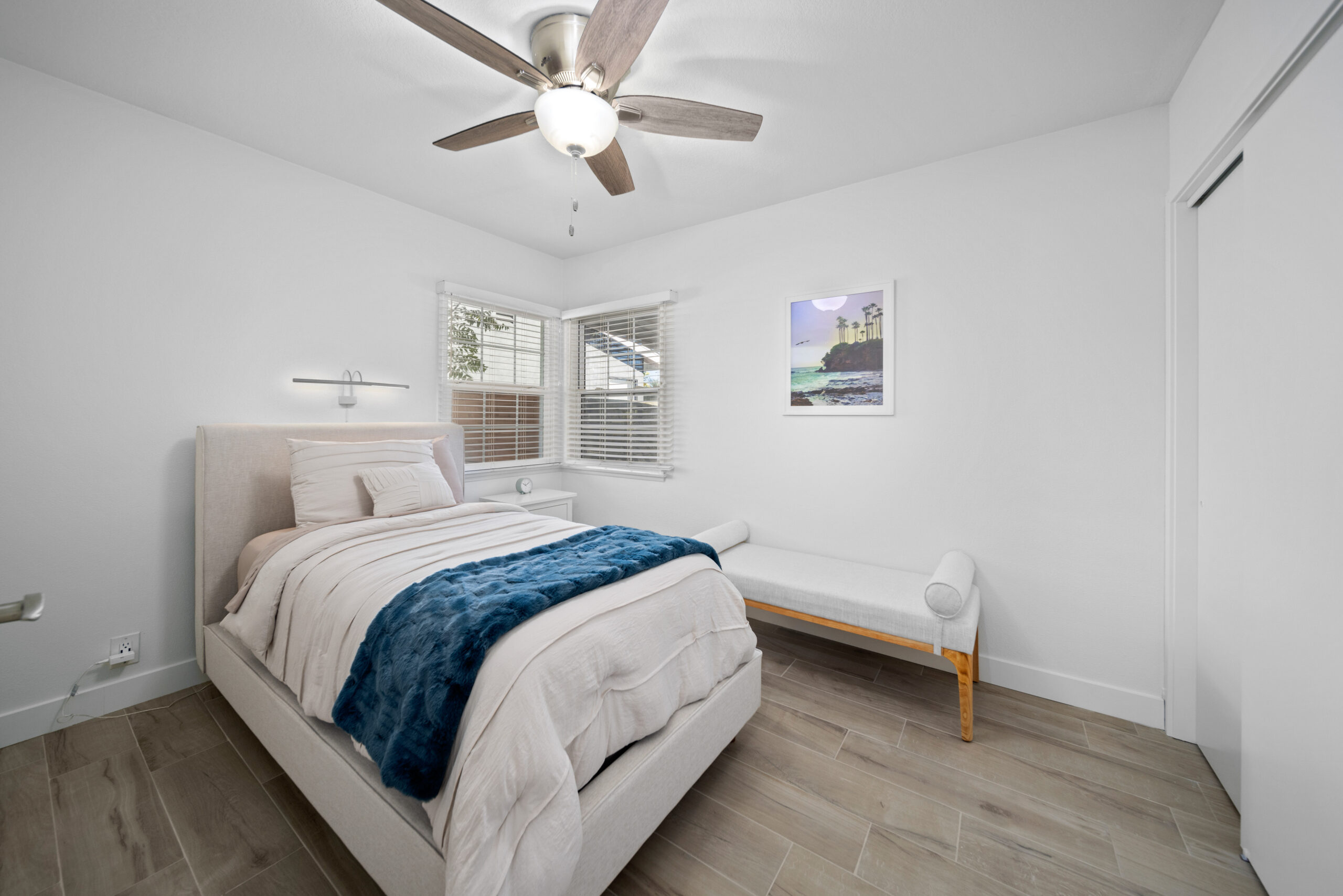 Single bed with white decor and corner windows