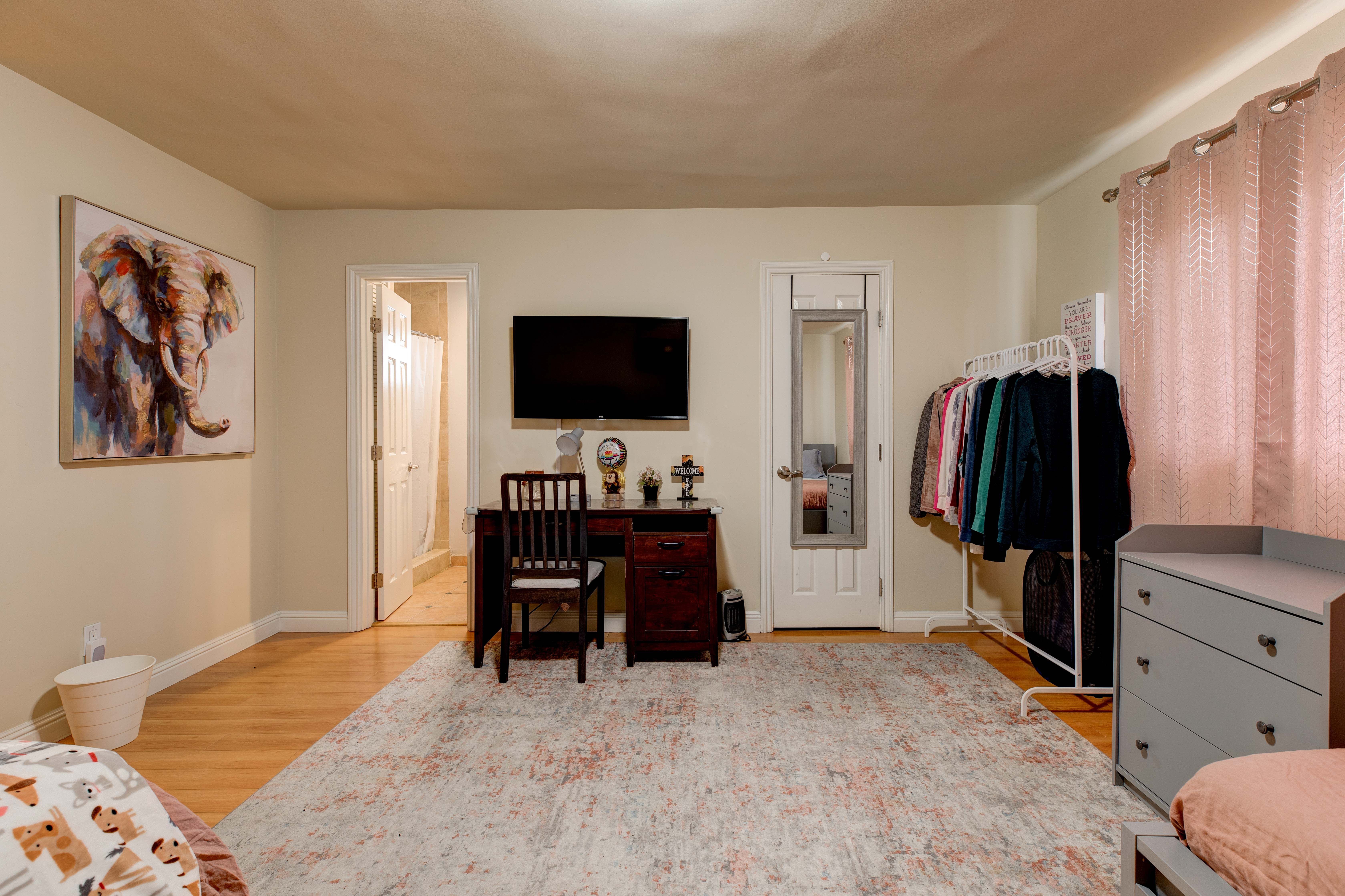 Shated bedroom with two beds, a desk, and a TV.