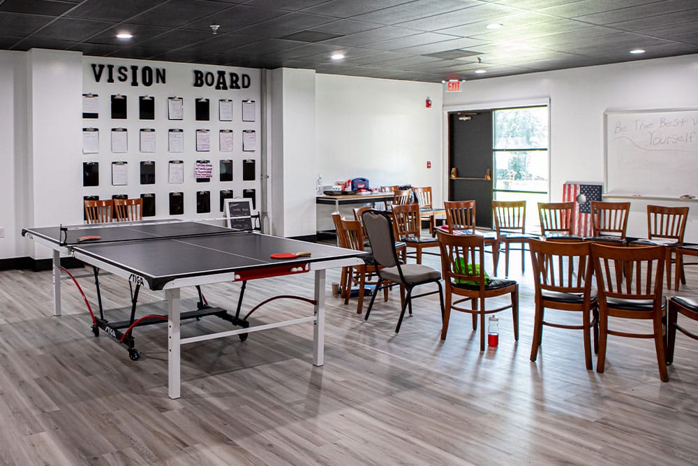 Ping pong table and chairs in a bright group activity room