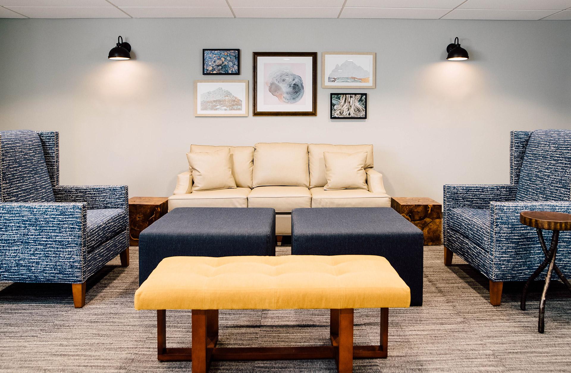 Group therapy room with sofa, chairs, and ottomans