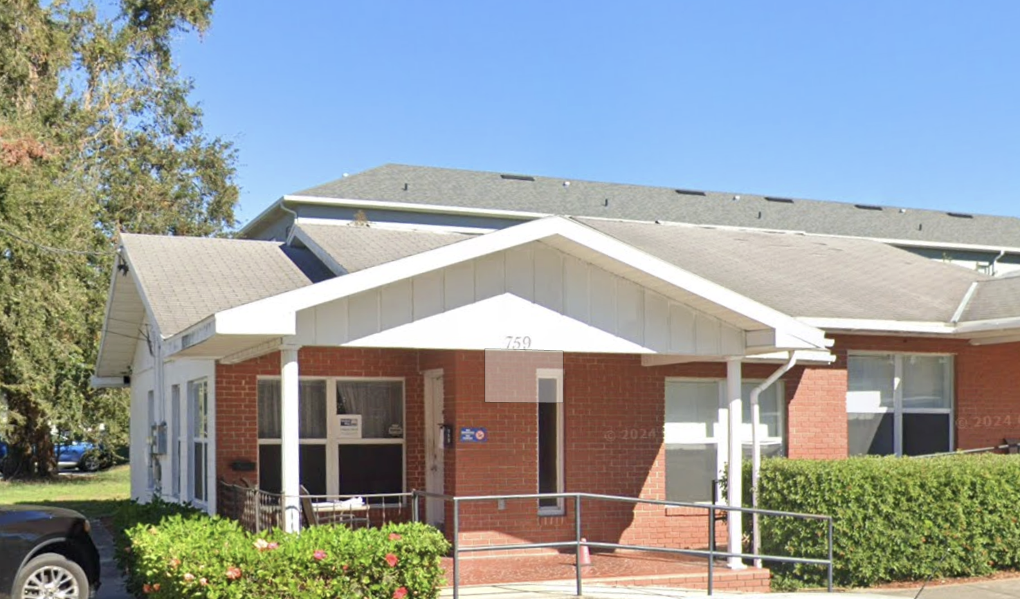 Brick building with white trim and ramp at front entrance