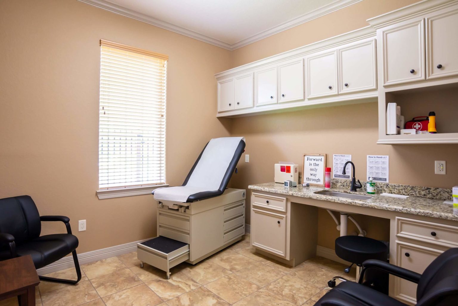 A clean medical exam room with a treatment bed and counter.