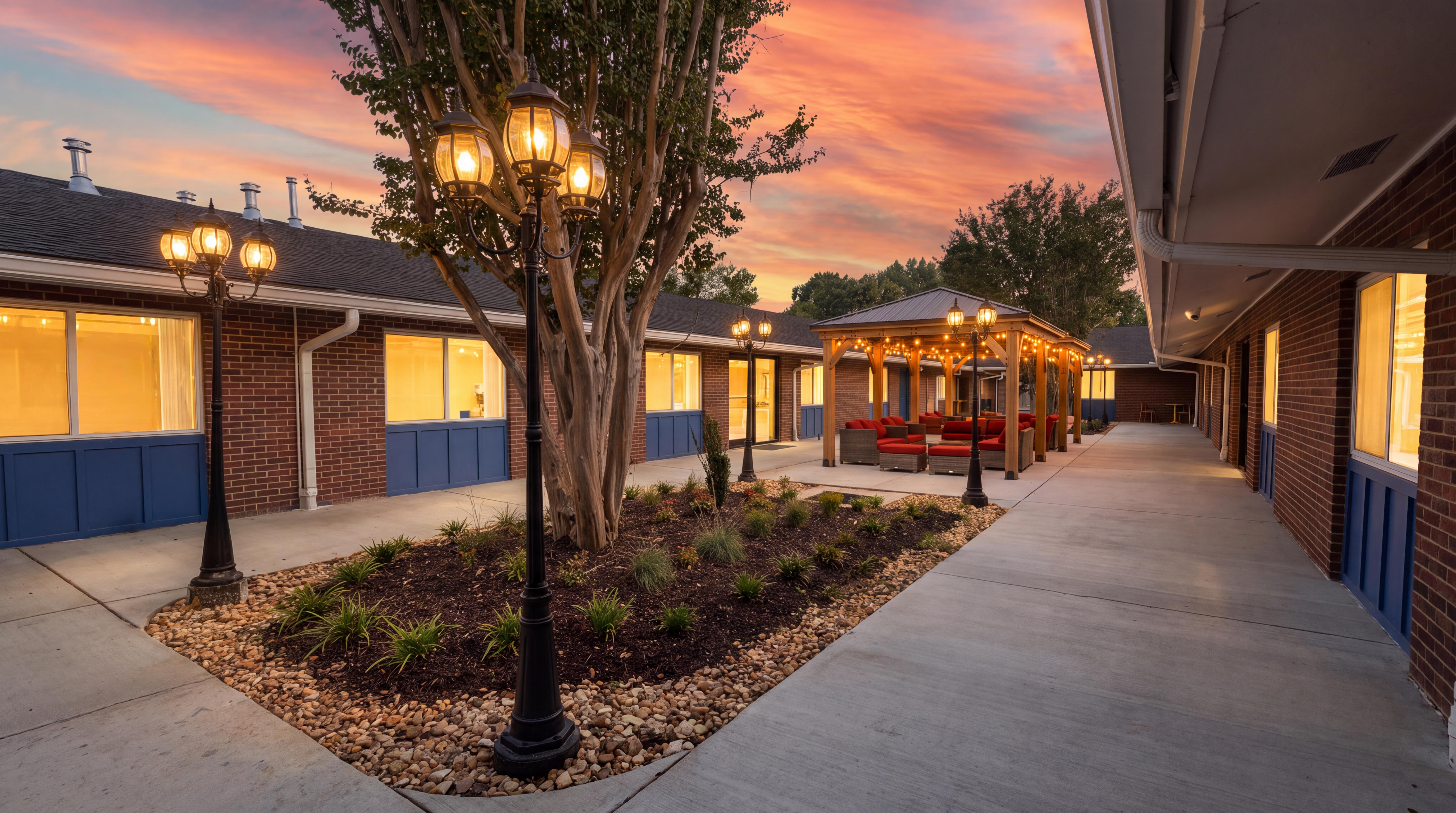 Courtyard walkway with trees and facility buildings at sunset