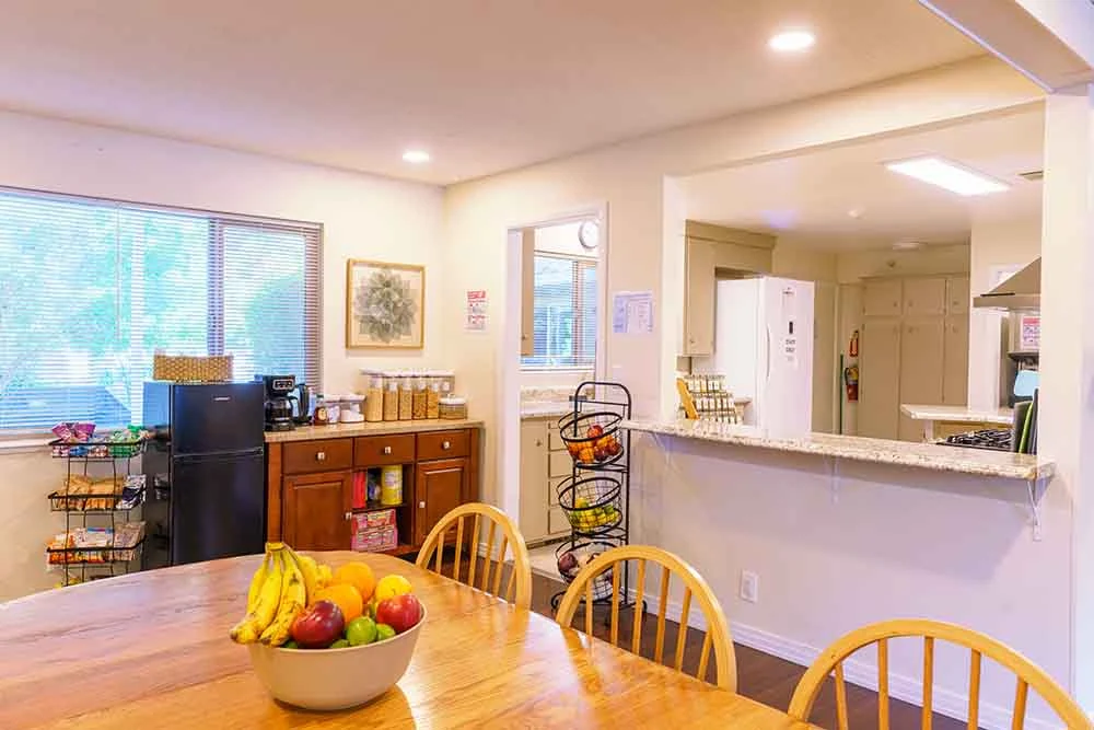 Dining table with fruit bowl beside kitchen serving counter