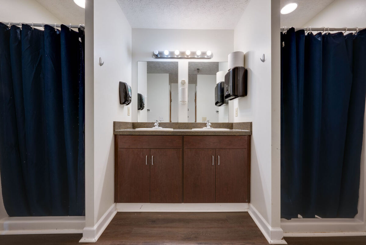 Bathroom with double sinks, dark wood cabinets, and shower curtains.