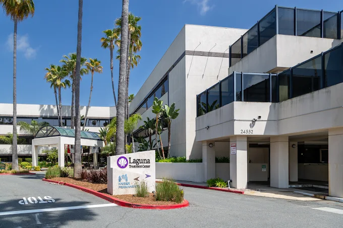 White multi-story hospital with palm trees and entrance sign