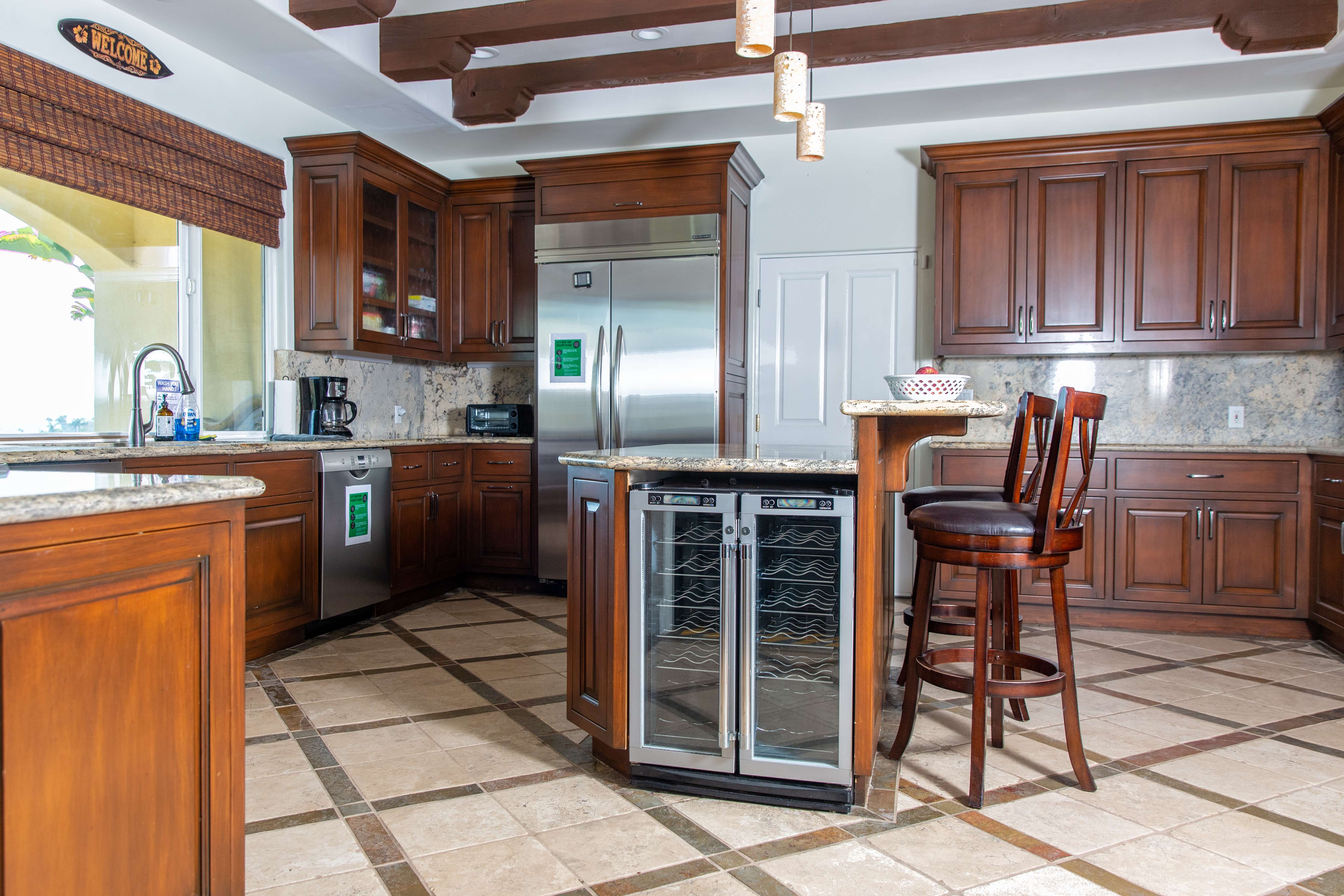 Large kitchen with wood cabinets, marble counters, and bar stools