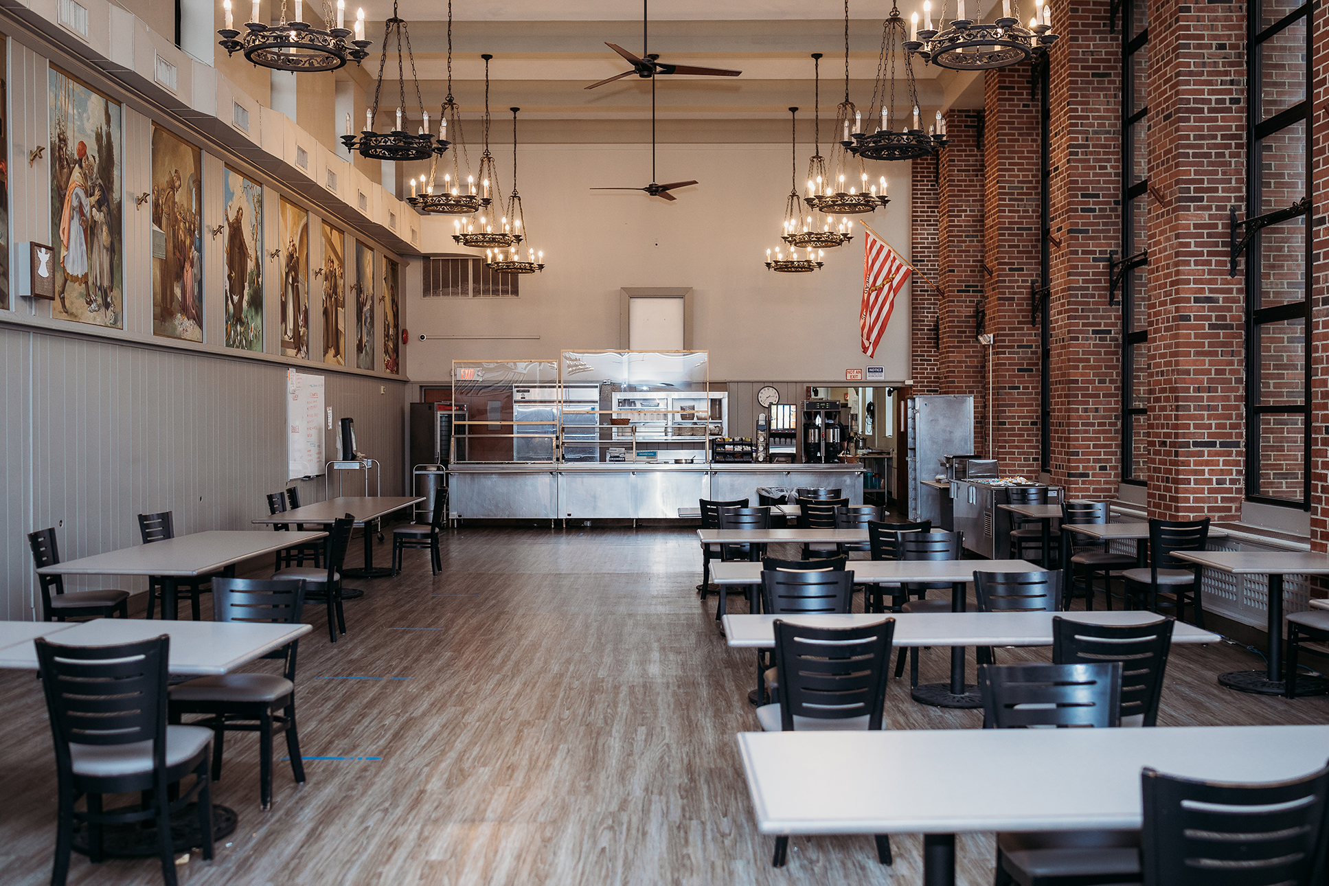 Large dining hall with tables, murals, and chandeliers