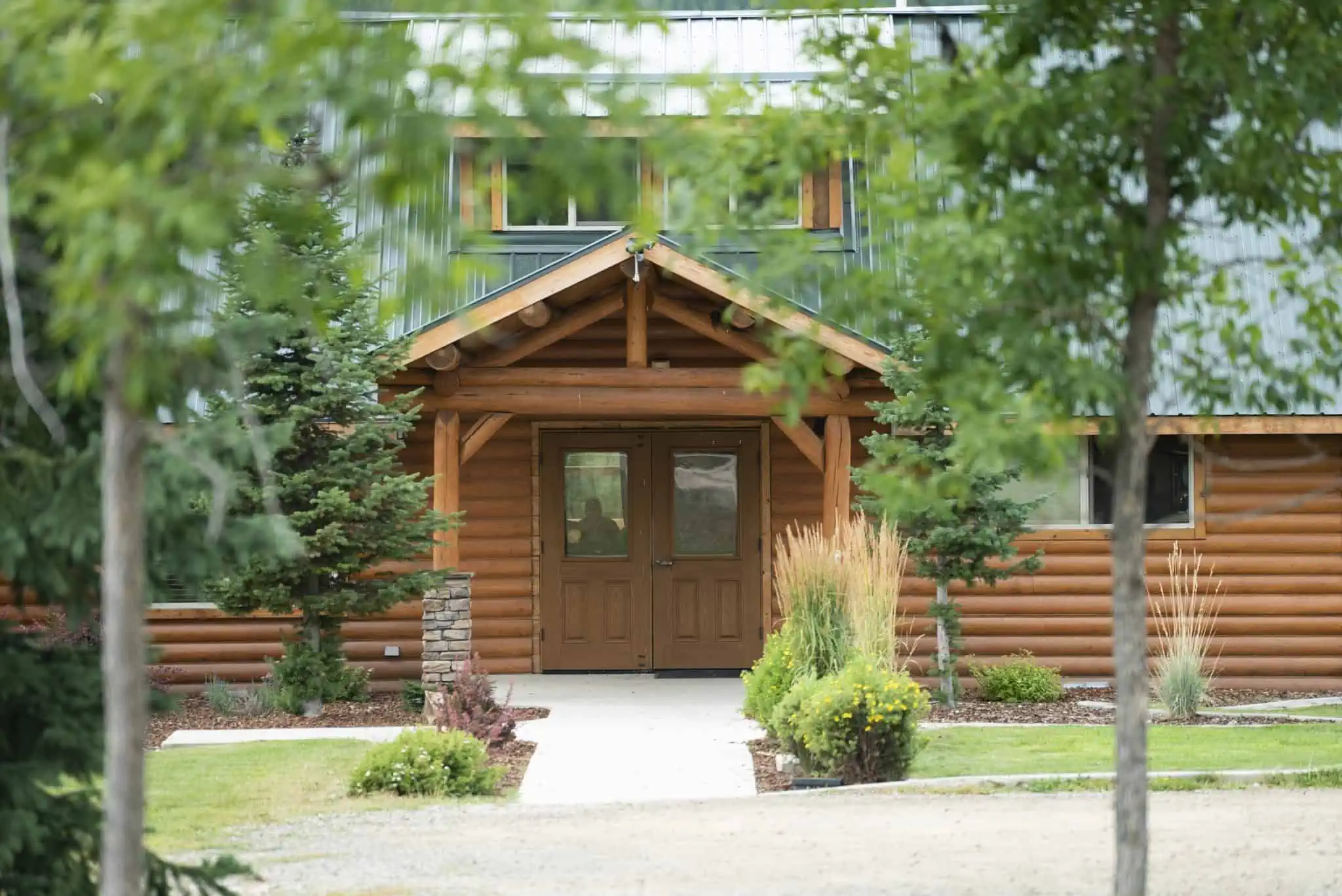 Log cabin entrance framed by trees and landscaping