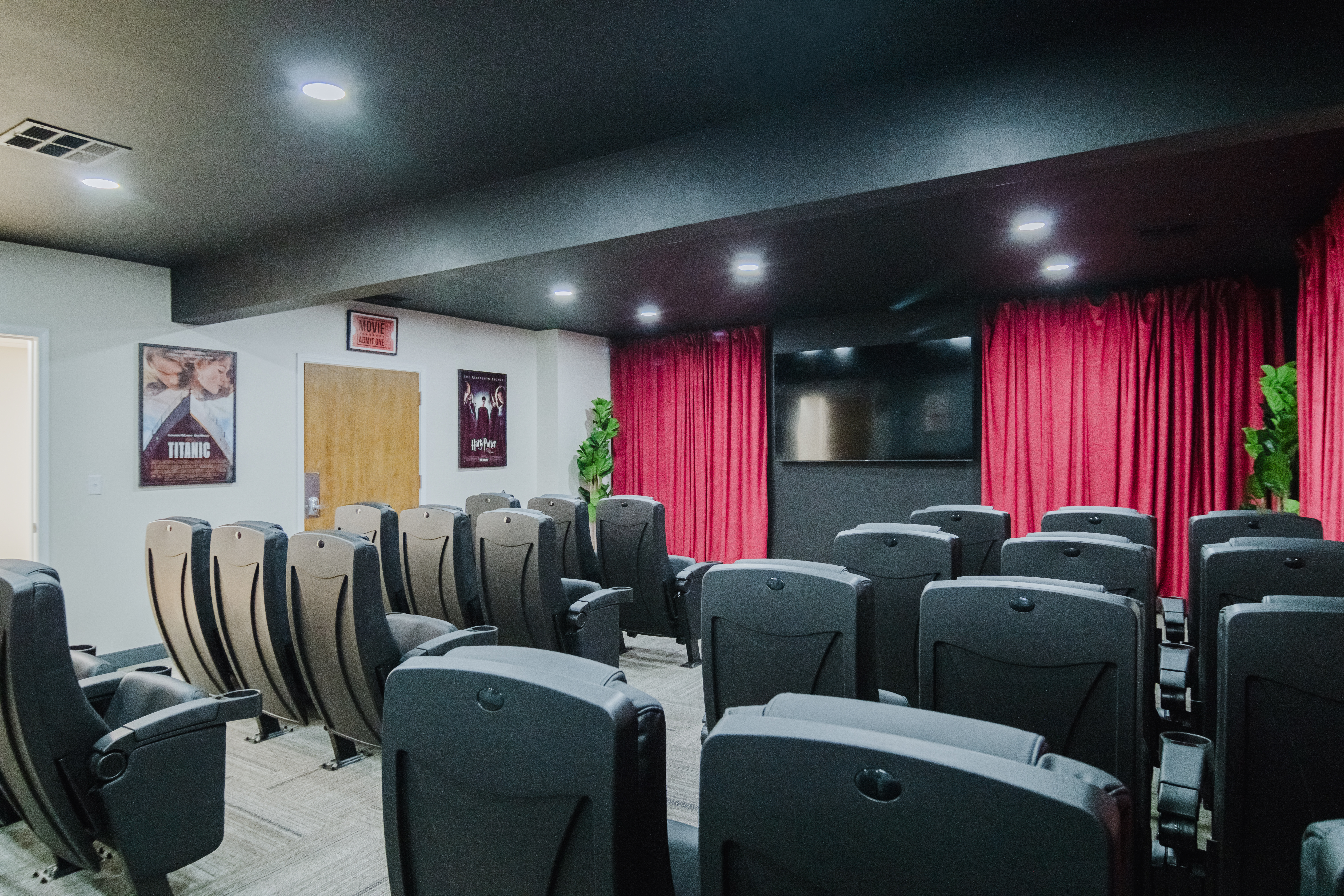 Theater room with recliner seating and large screen.
