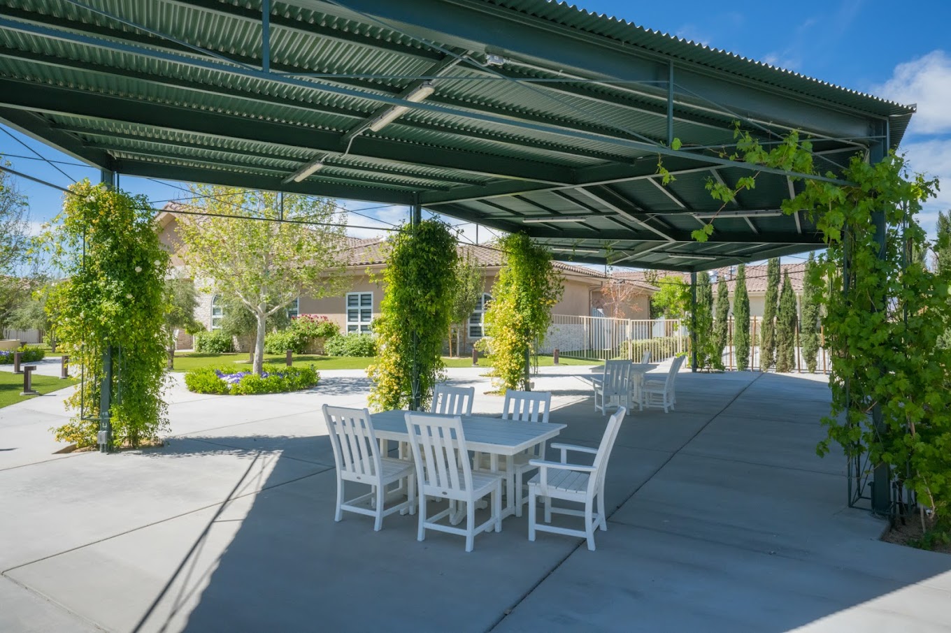Outdoor seating area with greenery and a covered patio.