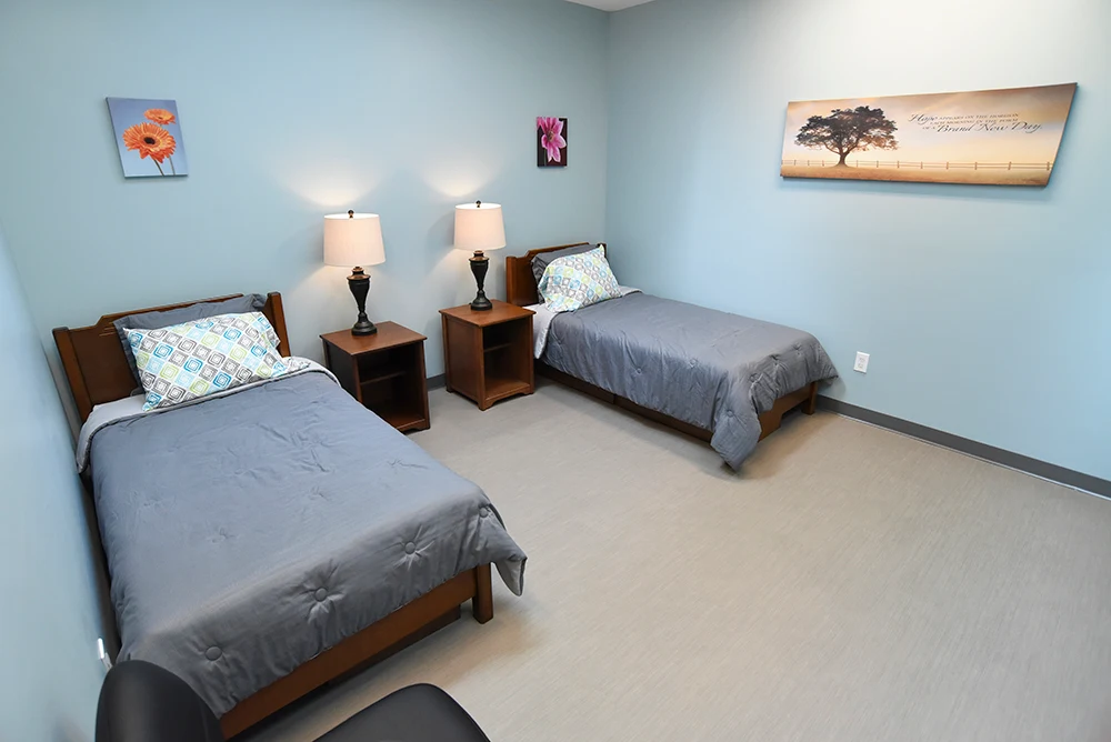Shared bedroom with two twin beds, lamps, and bedside tables