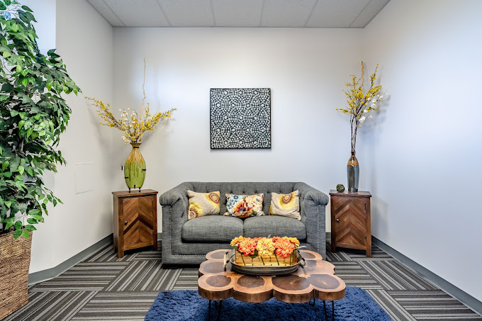 Waiting area with a sofa, plants and artwork.