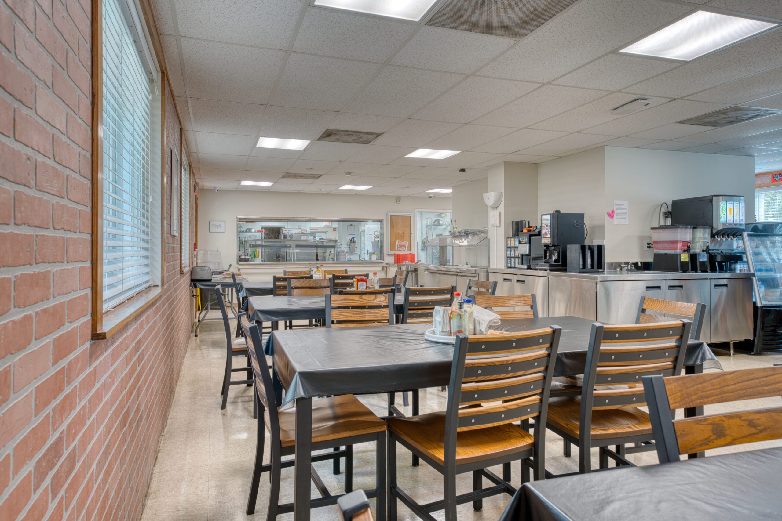 Cafeteria with dining tables, drink machines, and serving area.