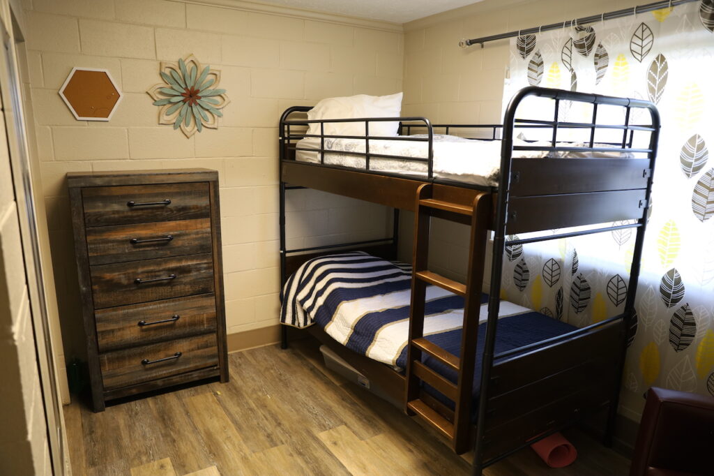 Room with bunk beds and wooden dresser near window