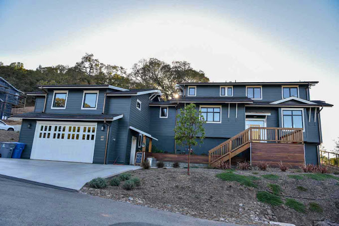 Modern gray rehab home with garage and driveway