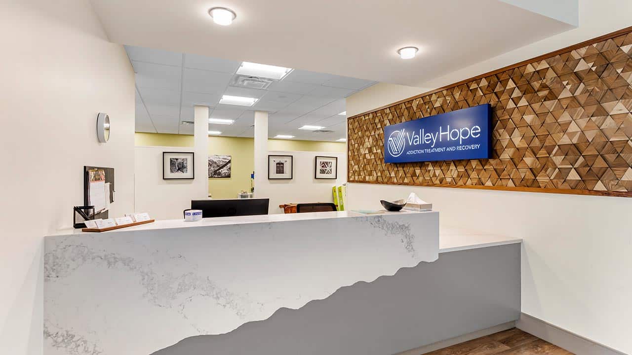 Modern rehab center reception with marble desk and wood decor