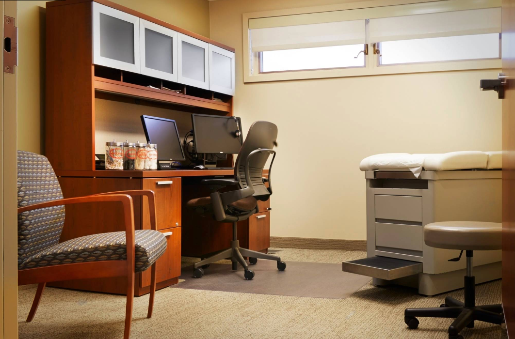 Private consultation room with desk, chairs, and exam table