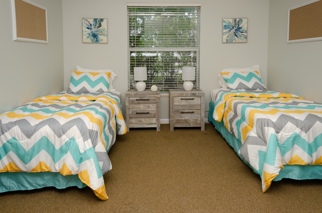 Twin beds with colorful bedding and window view
