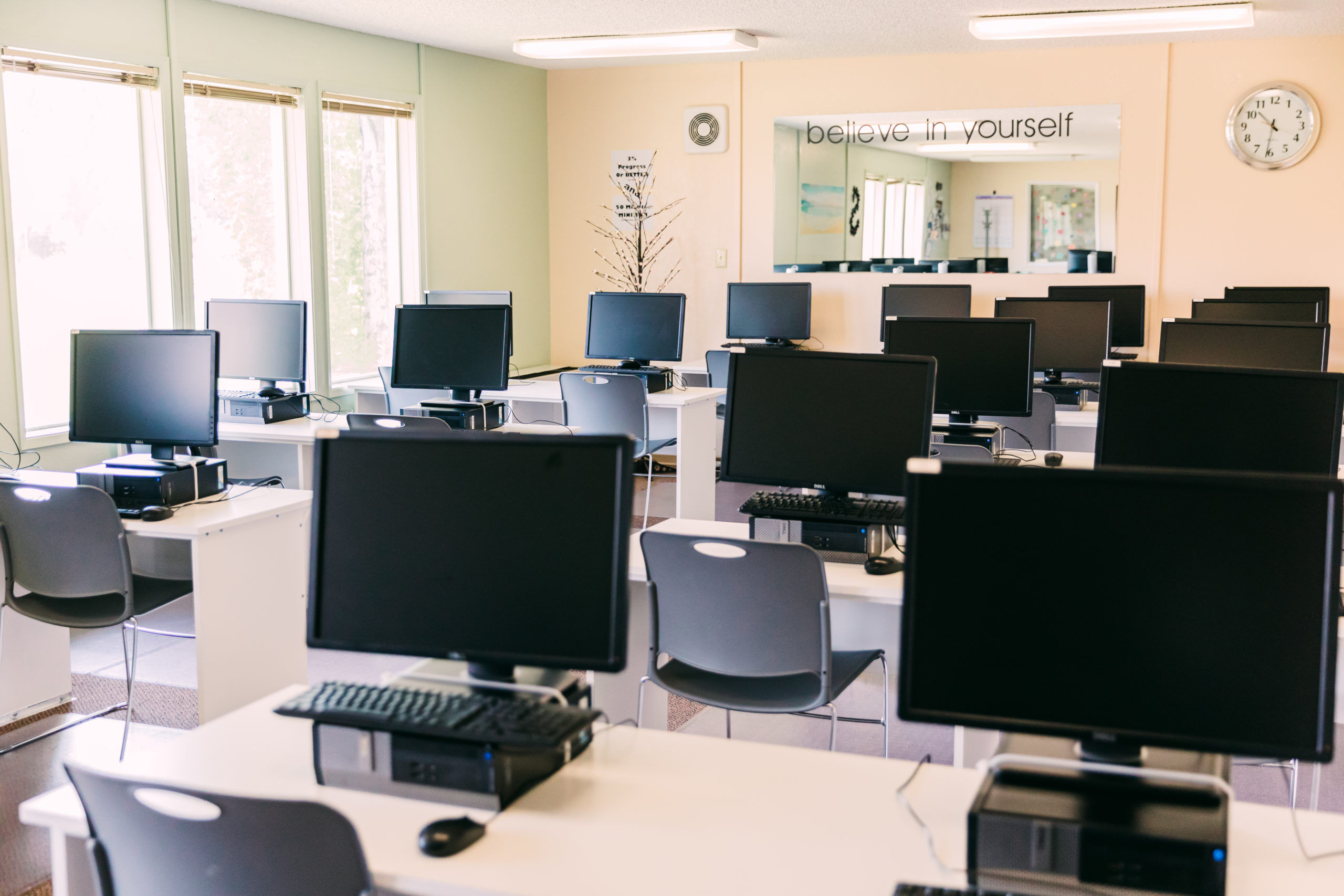 Computer lab with rows of monitors and chairs