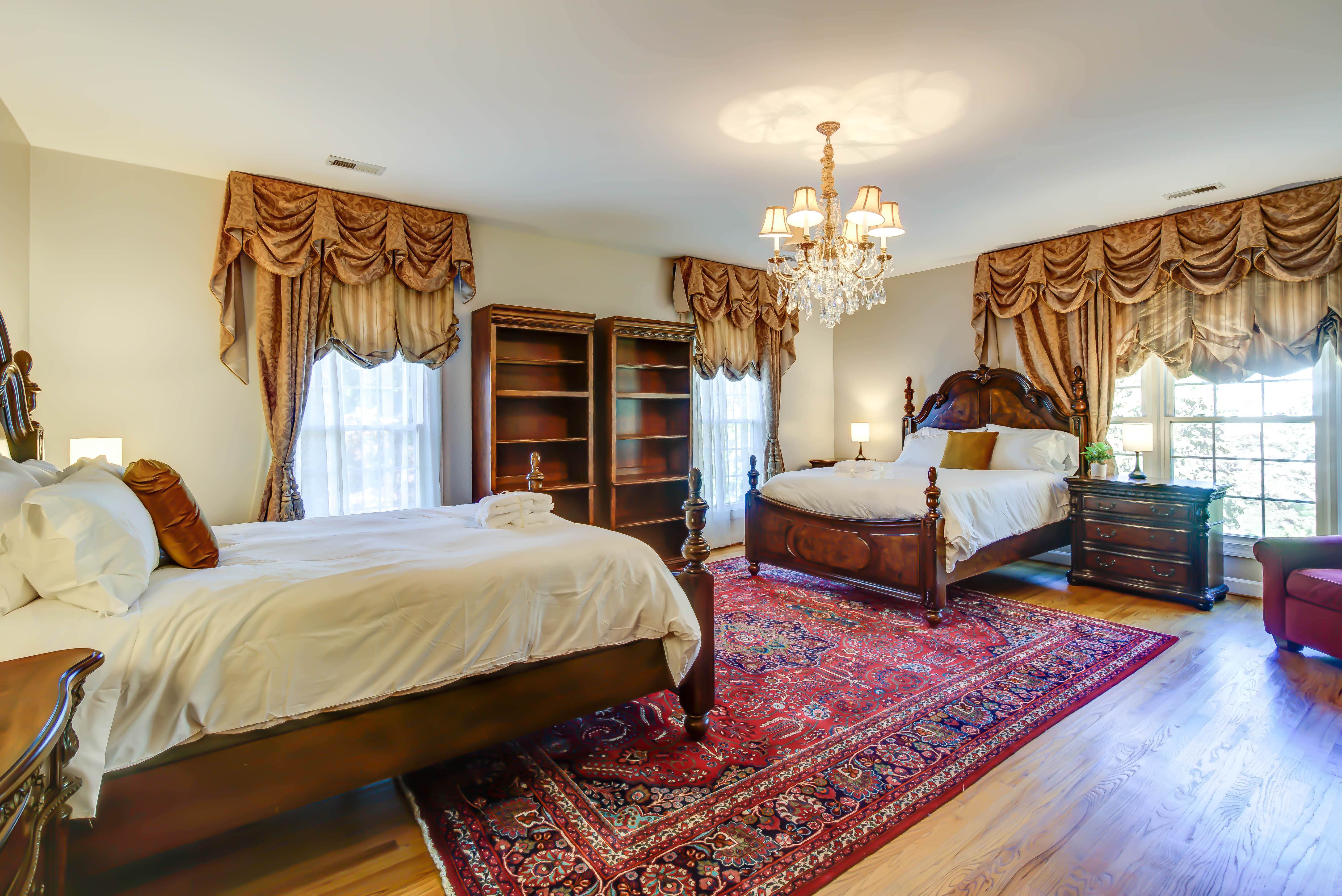 Room with two beds, ornate rug, and chandeliers
