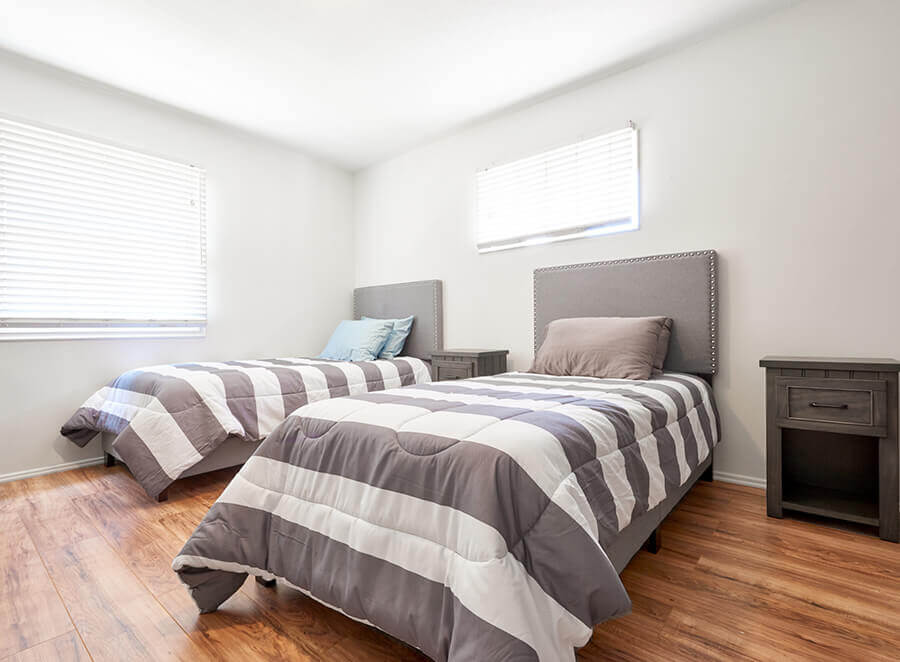 Two twin beds with striped bedding in bright room