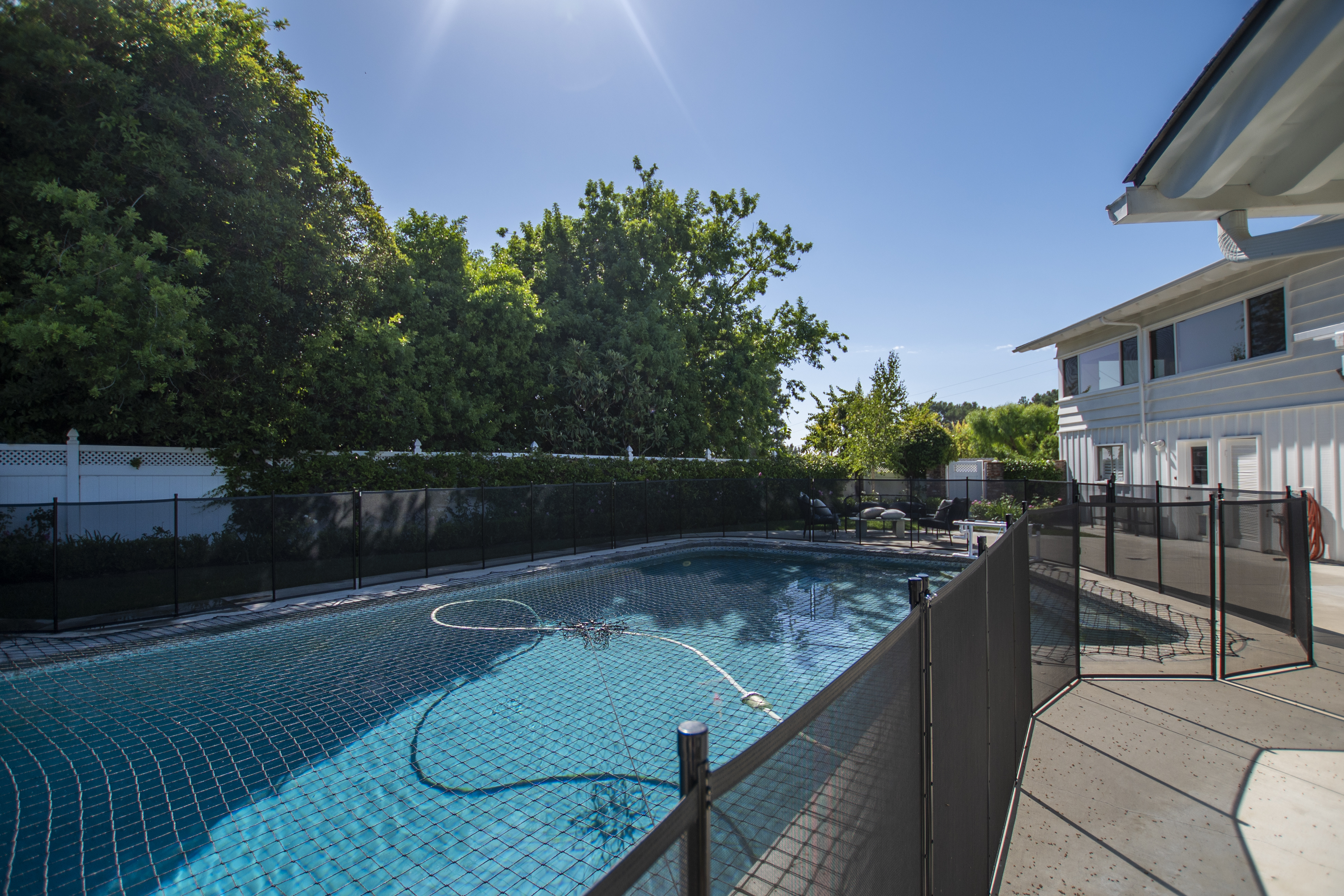 Pool with safety fence and lush trees around