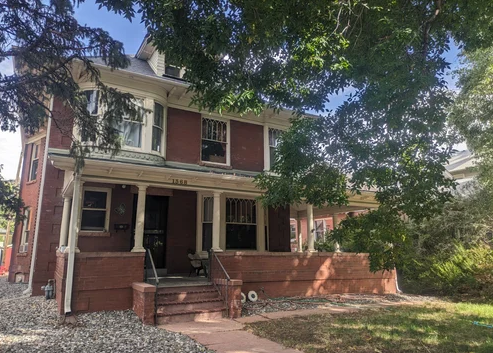Brick residential building with shaded front porch