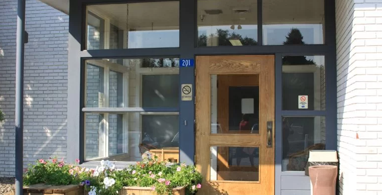 Building entrance with wood-framed glass door and flowers