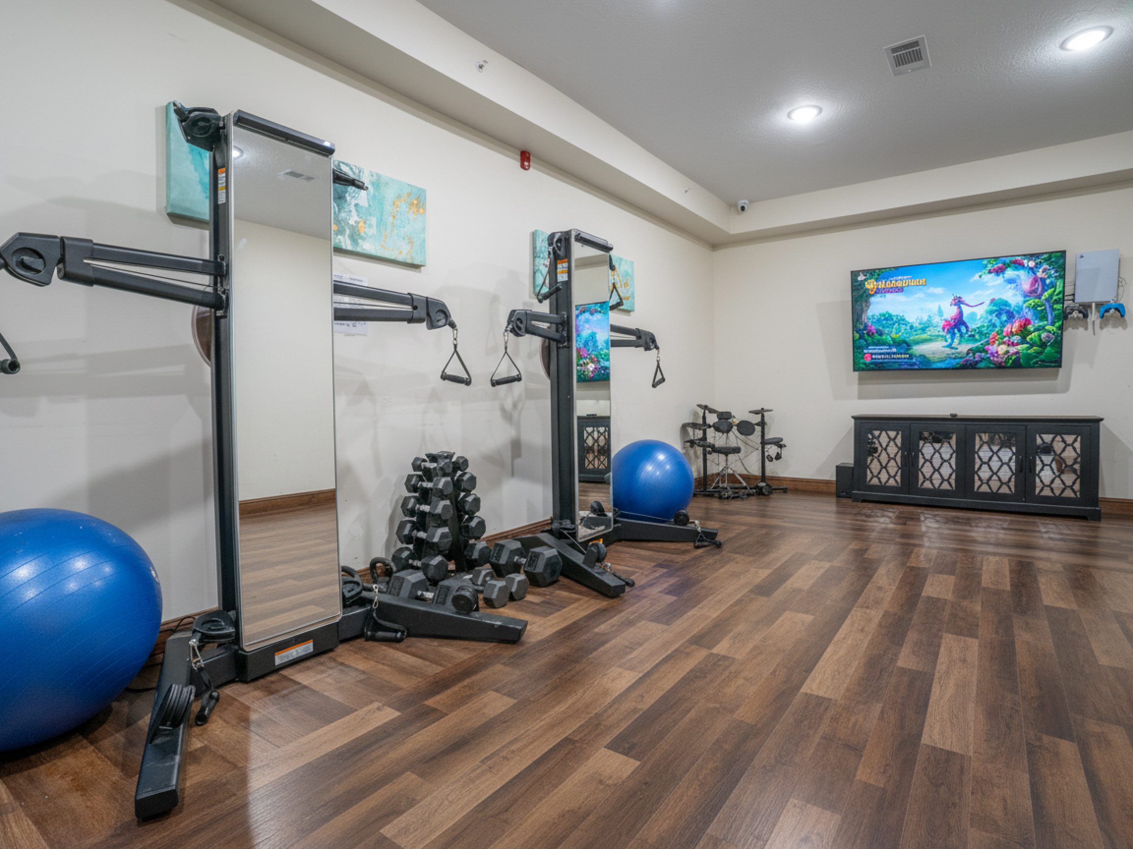 Indoor gym with weights, mirrors, and fitness machines.