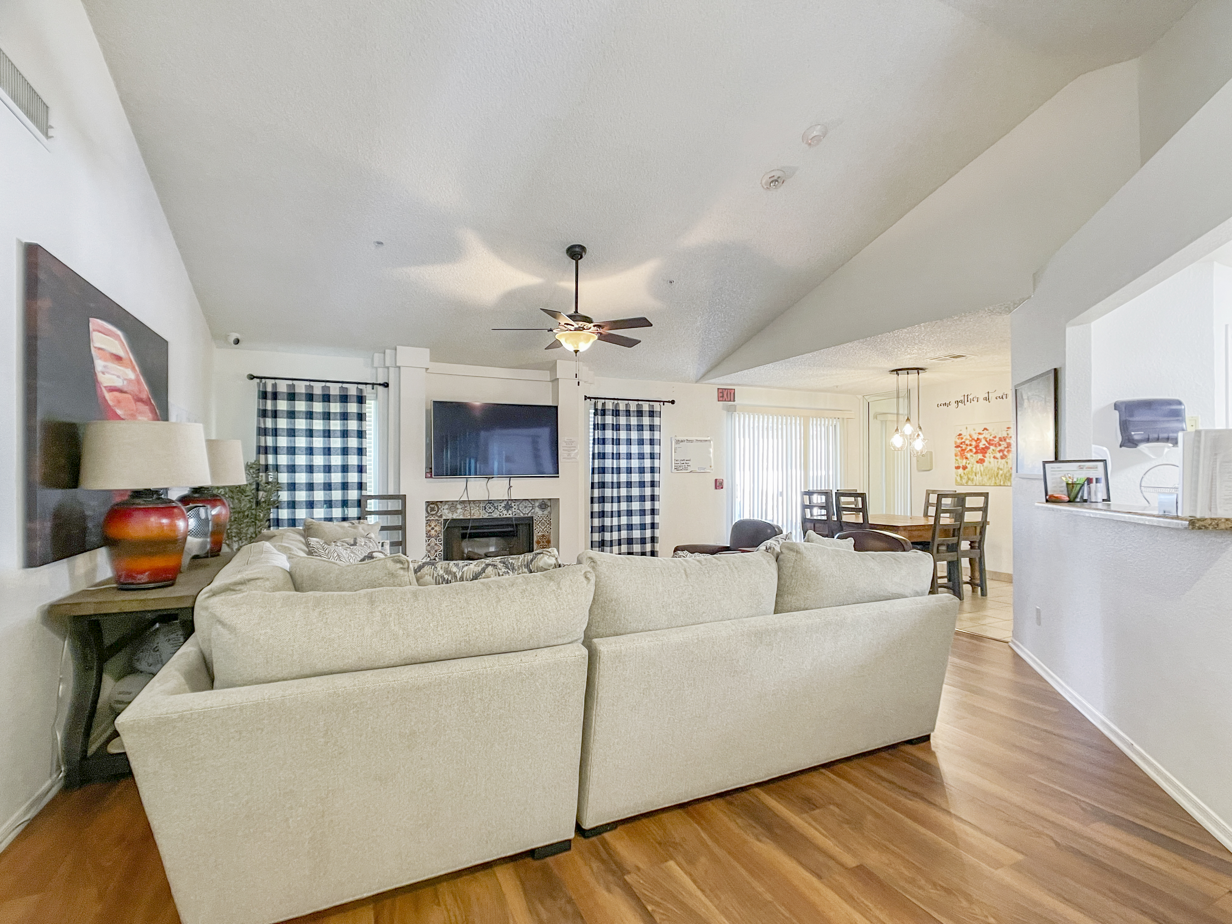 Living room with beige couches facing a fireplace and TV.