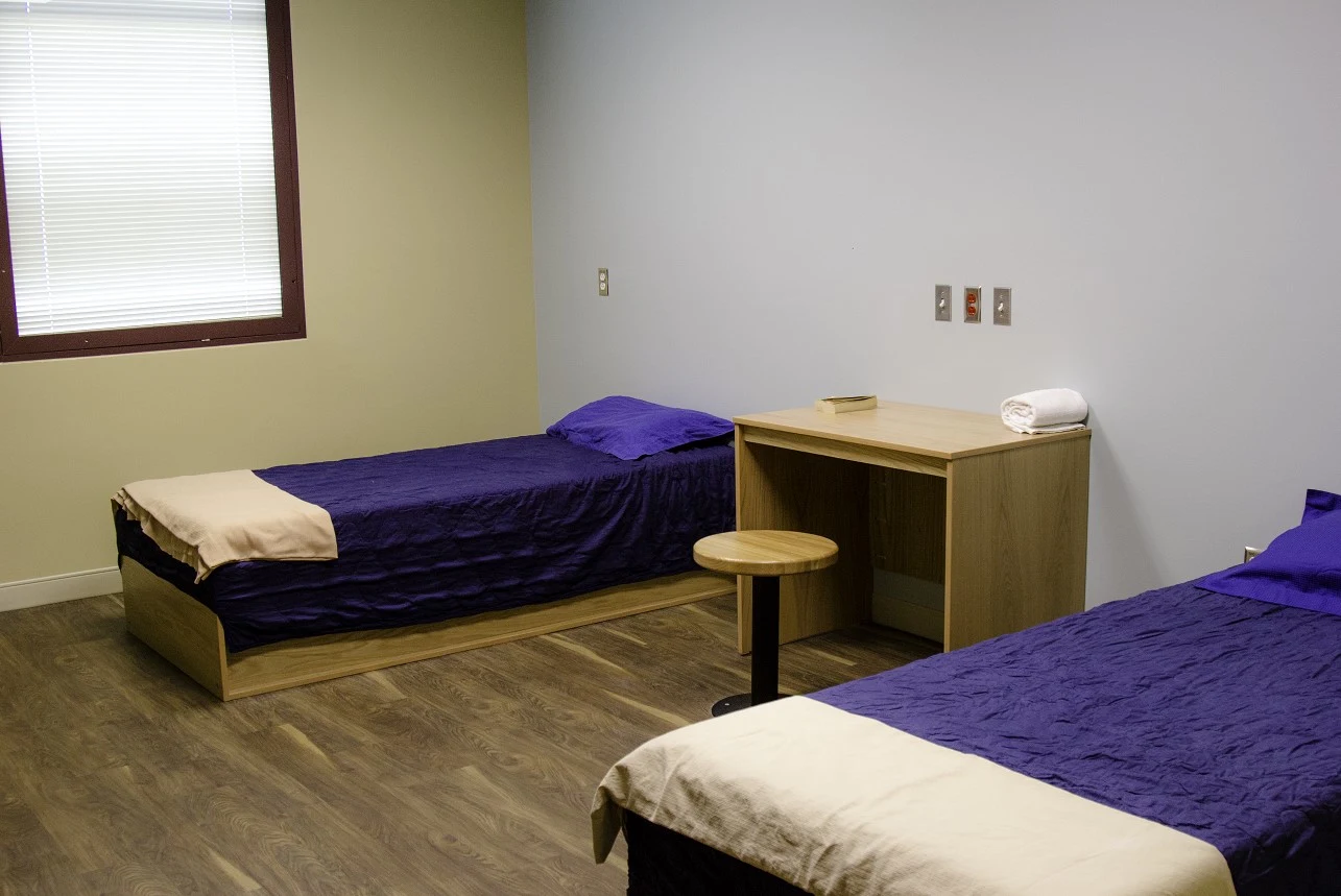 Shared patient bedroom with two beds and a desk.