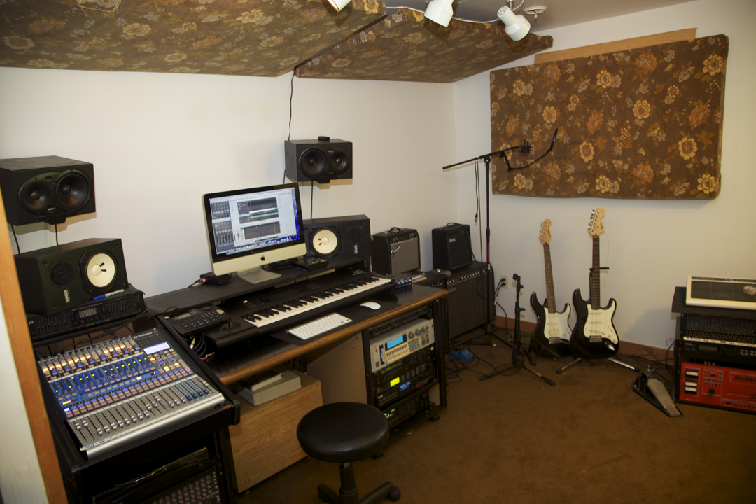 A modern music studio with guitars, speakers, and recording equipment
