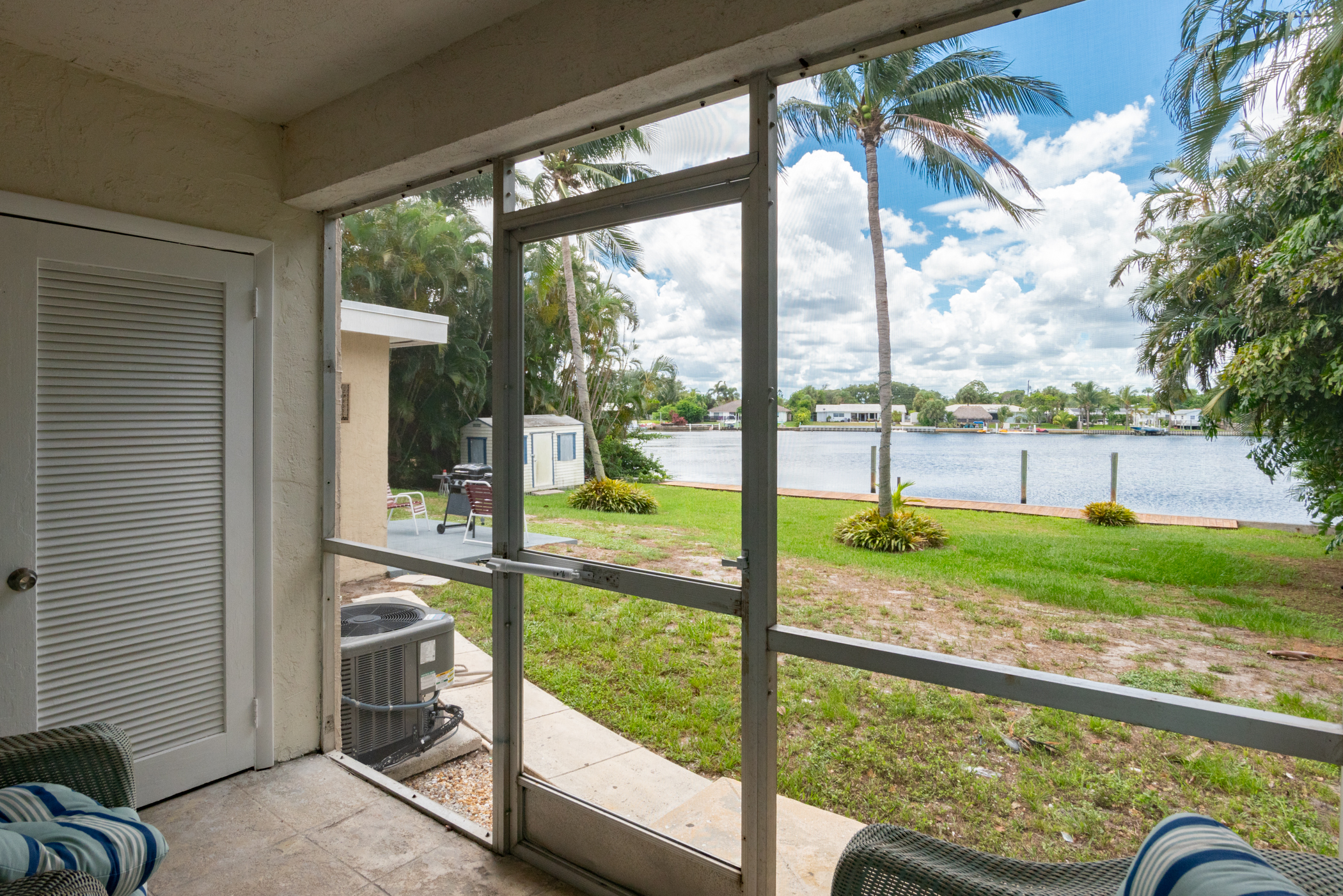 Screened patio overlooking water and green lawn