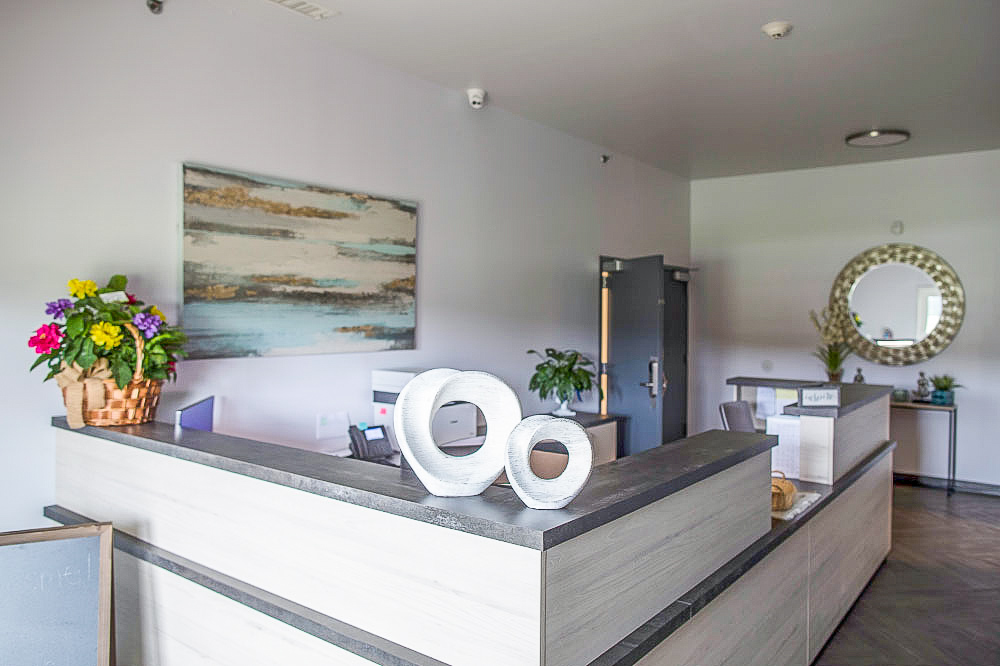 A reception area with a modern desk, artwork, and decorative items.