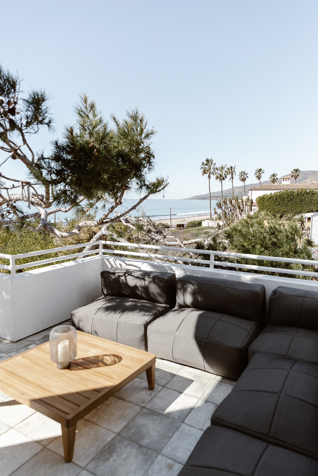 Rooftop seating area with ocean and palm tree views.