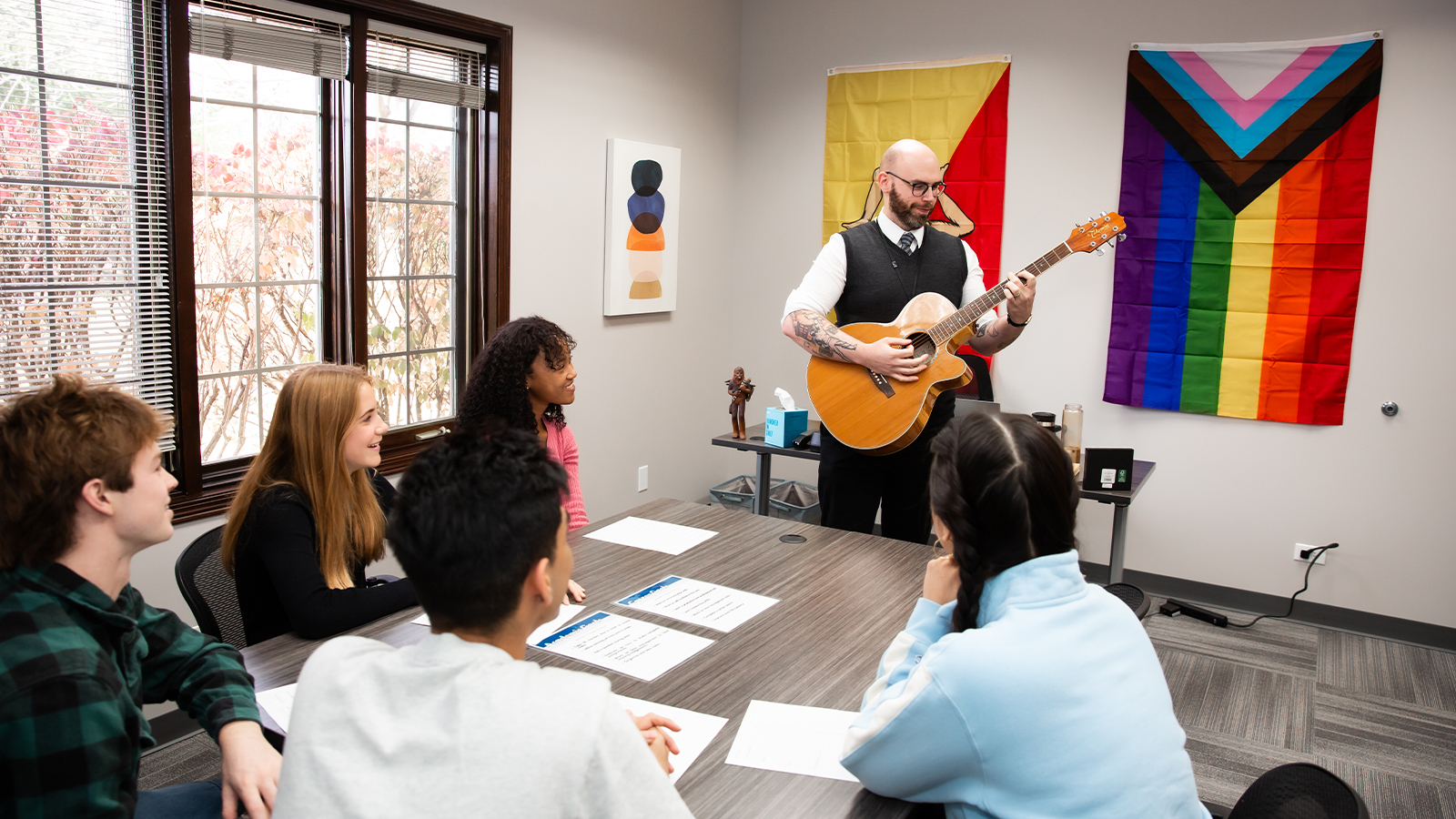 Recreational room with chairs at a table and a guitar.