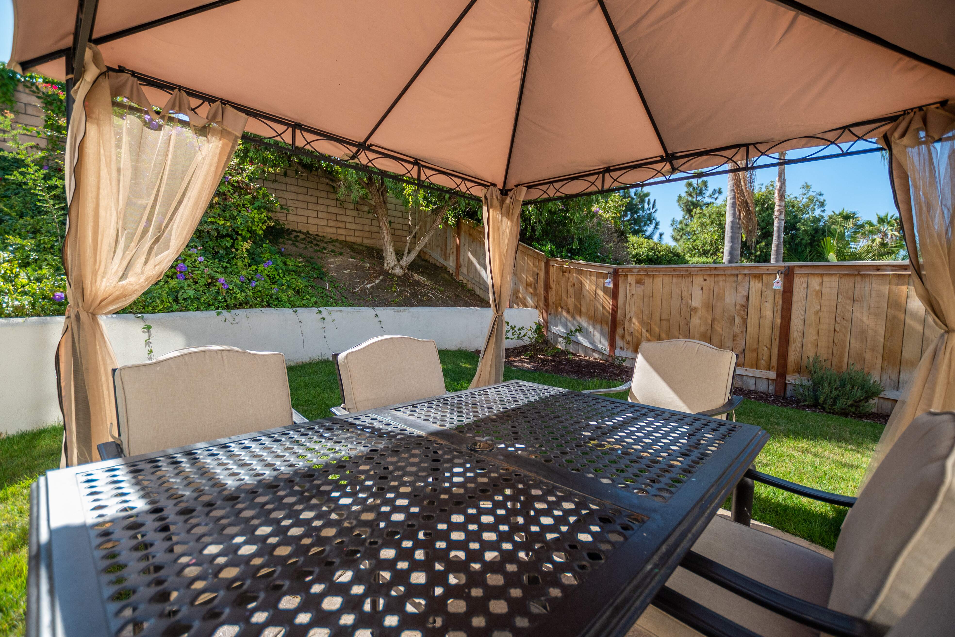 Patio table and chairs under a canopy with garden view