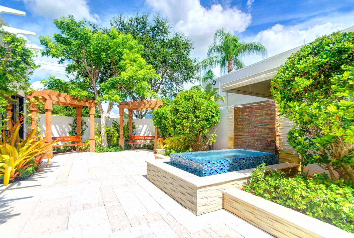Sunny courtyard with fountain, pergola, and lush greenery