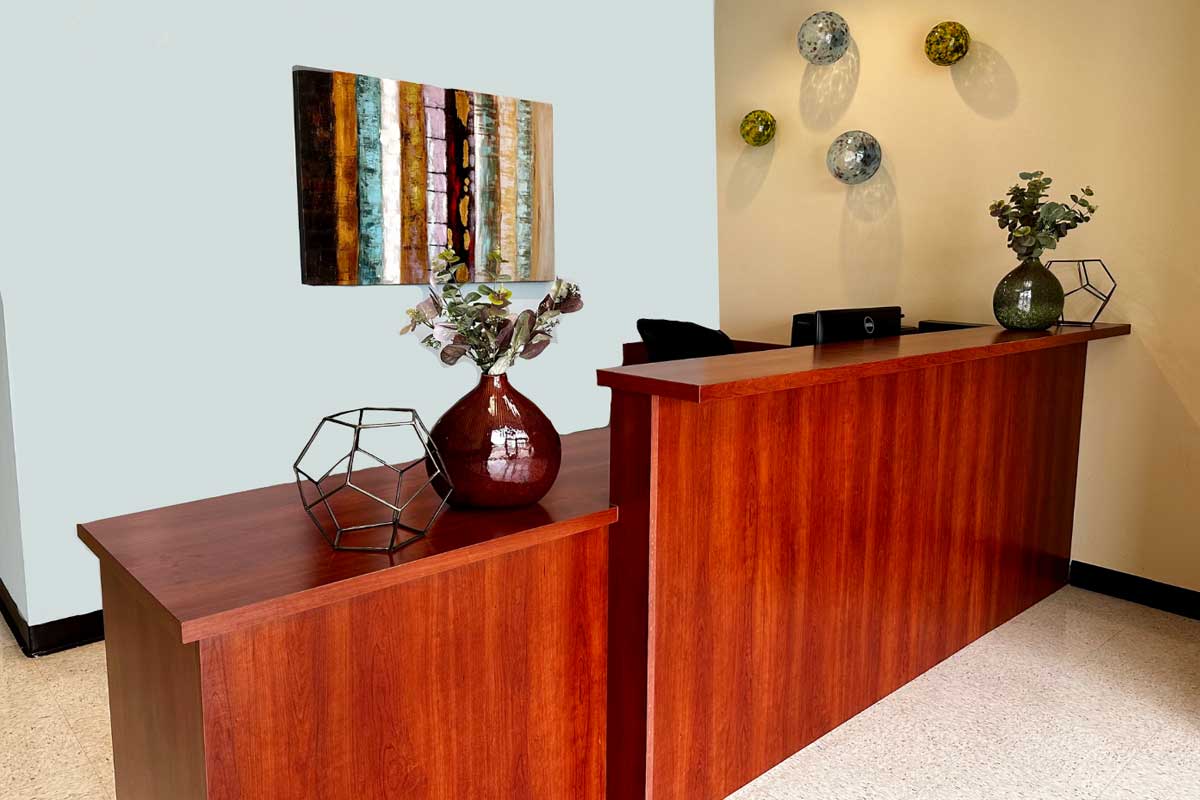 Front desk with a wooden counter and calming wall art in the reception area of Evoke Wellness