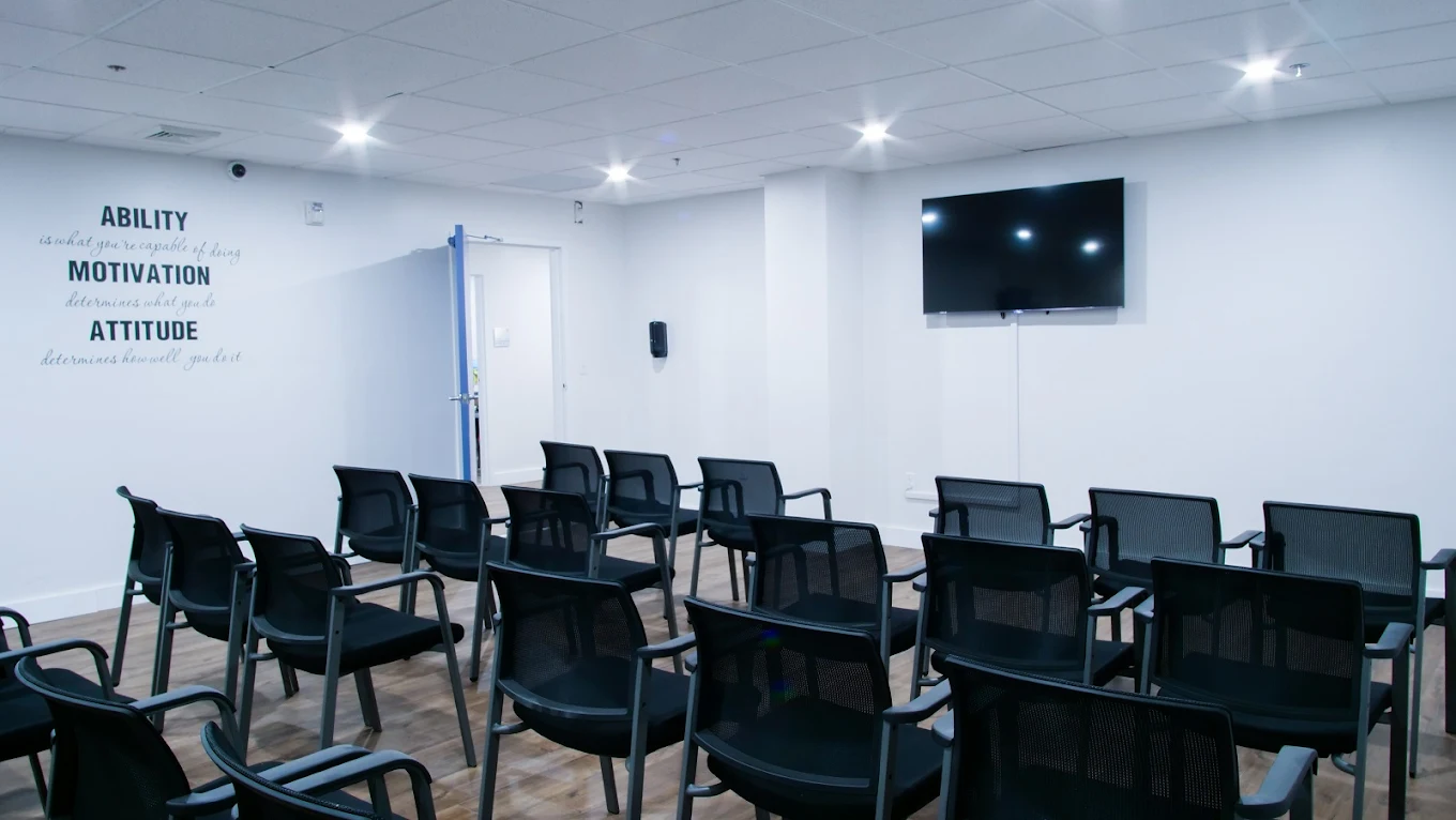 Meeting room with rows of chairs facing a TV and motivational quotes on the wall
