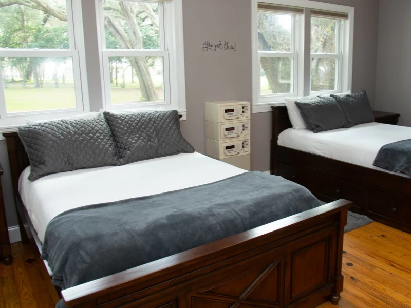 Bedroom with two beds and windows overlooking trees