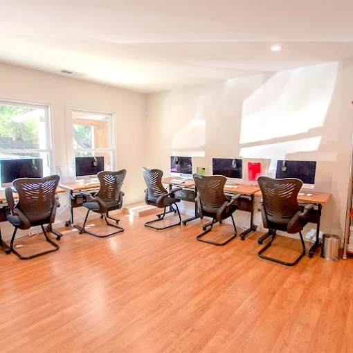 Computer lab with row of desks and black chairs