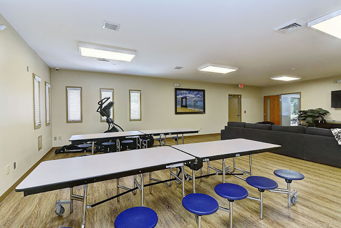 Common room with foldable tables, couch, and large wall TV.