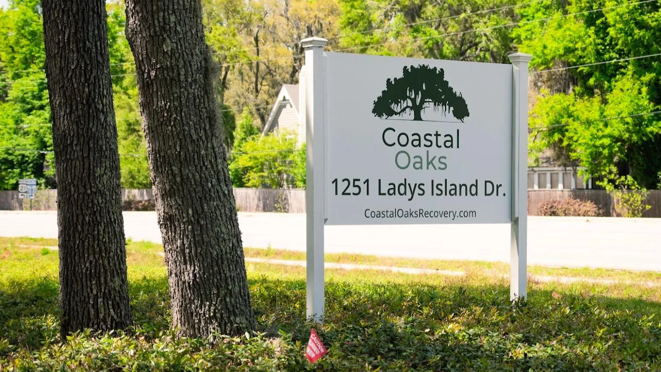 Coastal Oaks facility sign along a tree-lined roadside